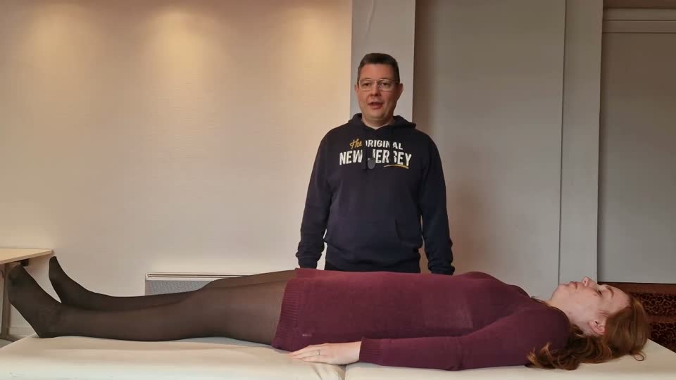 Praticien debout aux pieds du receveur, posture centrée avant le geste