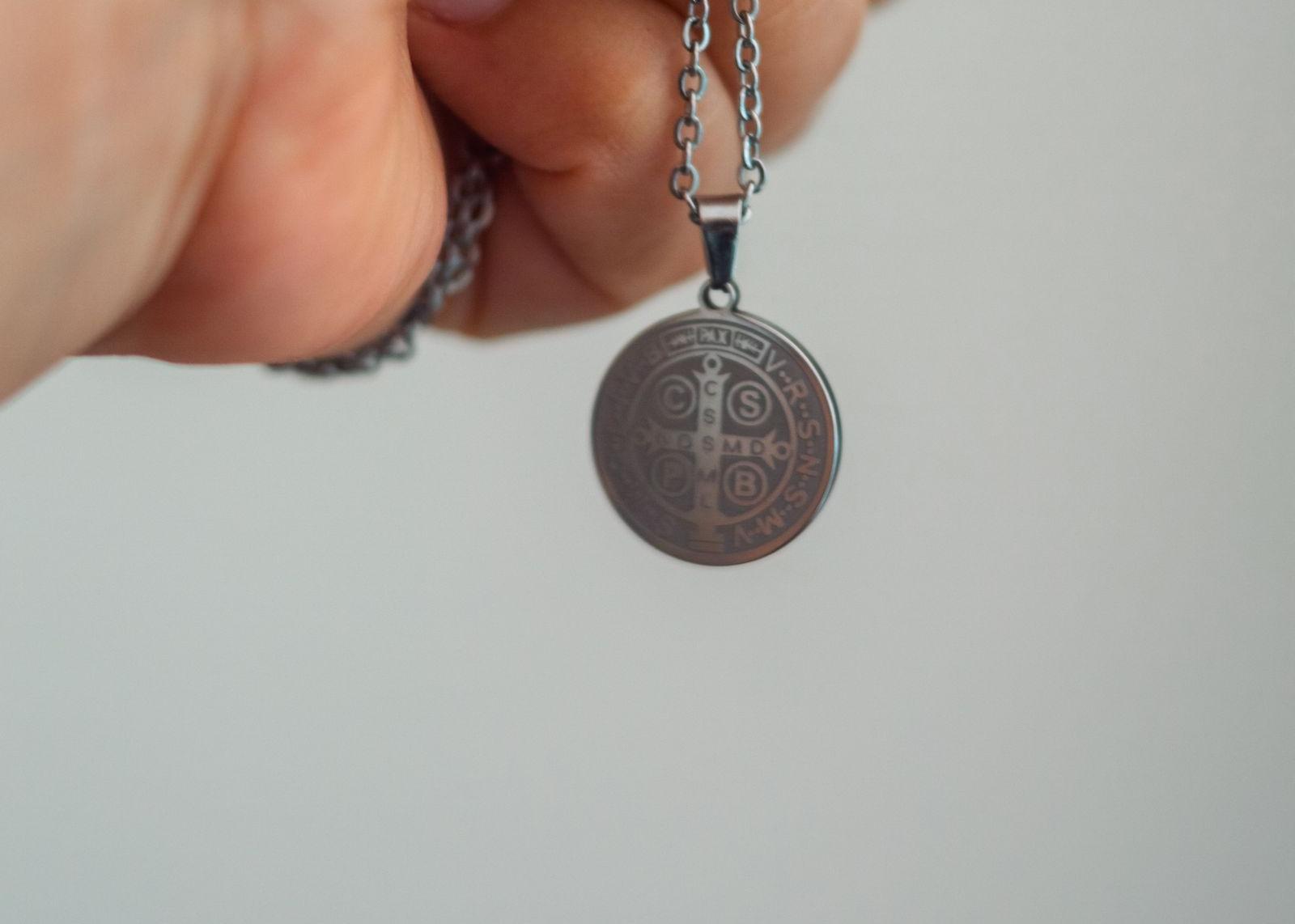 Médaille de Saint Benoît tenue en main, inscriptions CSPB visibles