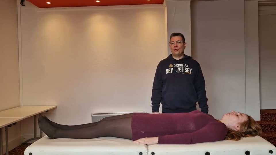 Praticien debout aux pieds du receveur, posture calme et centrée